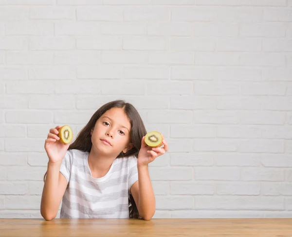 Young Hispanic Kid Sitting Table Eating Kiwi Confident Expression Smart — Stock Photo, Image