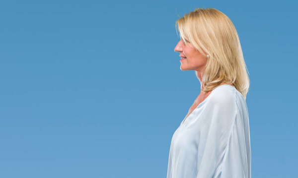 Middle age blonde business woman over isolated background looking to side, relax profile pose with natural face with confident smile.