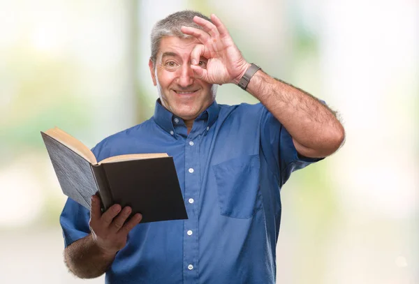 英俊的资深教师男子阅读一本书在孤立的背景与快乐的脸微笑做 标志与手在眼睛看通过手指 — 图库照片