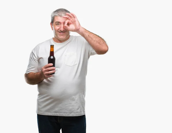 指の間から見て目に手で サインをして笑っている幸せそうな顔で孤立した背景にビール瓶を飲んでハンサムな年配の男性 — ストック写真