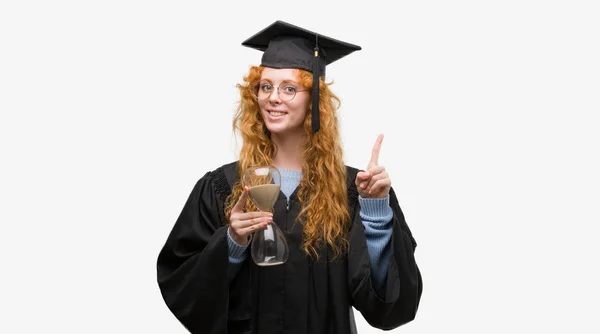 Giovane Studentessa Rossa Con Indosso Uniforme Graduata Che Tiene Clessidra — Foto Stock