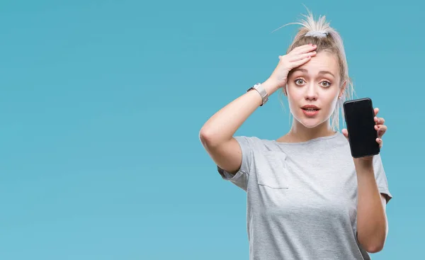 Young blonde woman showing screen of smartphone over isolated background stressed with hand on head, shocked with shame and surprise face, angry and frustrated. Fear and upset for mistake.