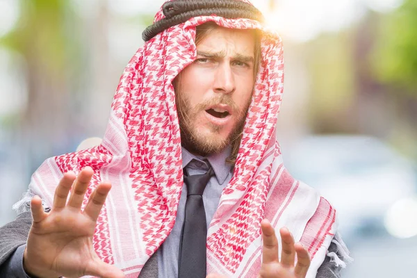 年轻英俊的阿拉伯男人带着长发戴着 Keffiyeh 在孤立的背景下害怕和恐惧的表情 用手停止手势 在震惊中大叫 恐慌概念 — 图库照片