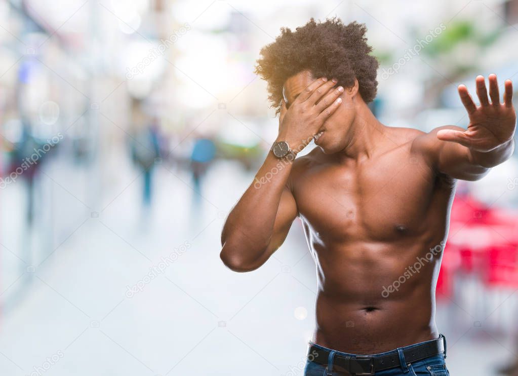 Afro american shirtless man showing nude body over isolated background covering eyes with hands and doing stop gesture with sad and fear expression. Embarrassed and negative concept.
