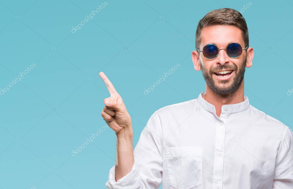 Young handsome man wearing glasses over isolated background with a big smile on face, pointing with hand and finger to the side looking at the camera.
