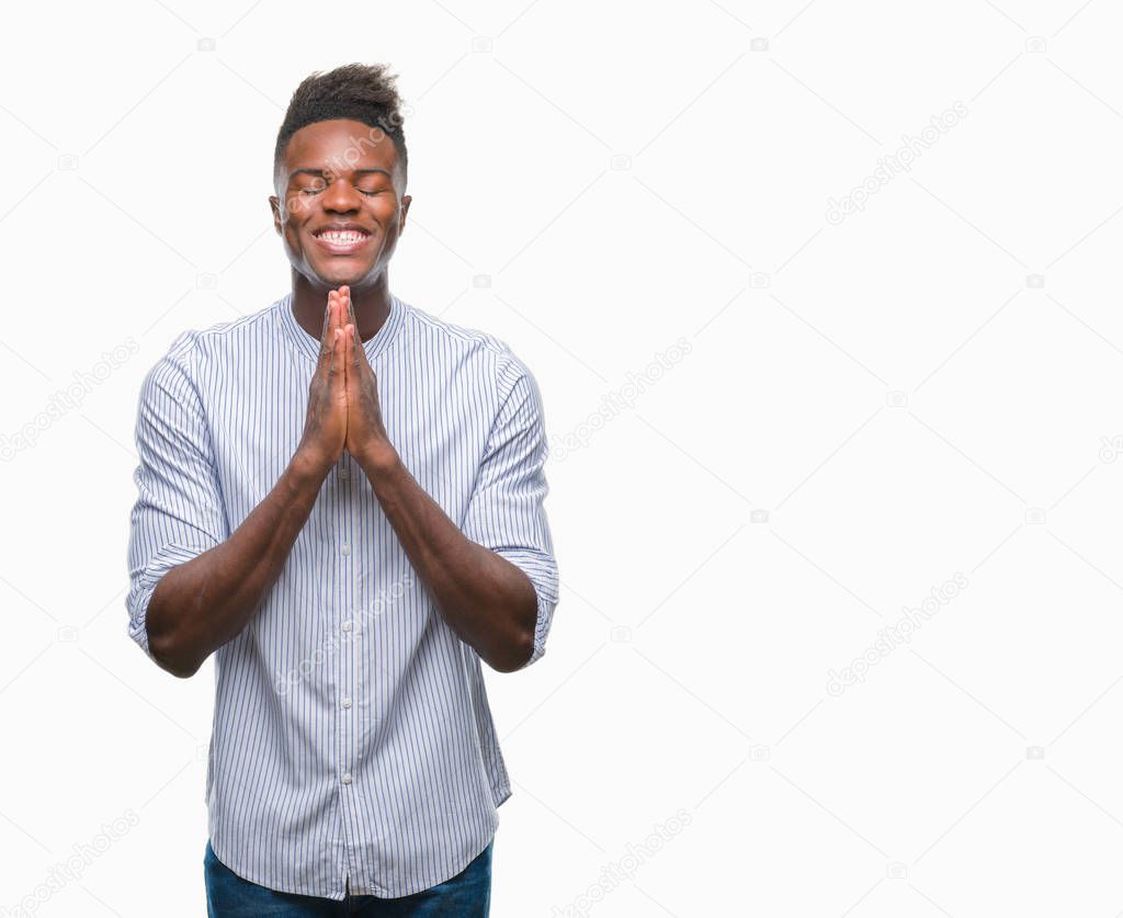 Young african american man over isolated background praying with hands together asking for forgiveness smiling confident.