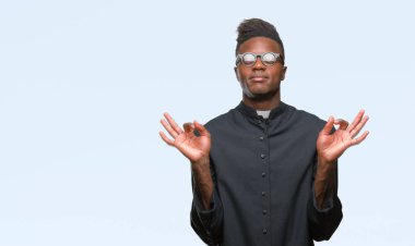 Genç Afro-Amerikan rahip adam izole arka plan üzerinde dinlenmek ve gülümseyen gözlerle parmak ile meditasyon jest yapıyor kapalı. Yoga kavramı.