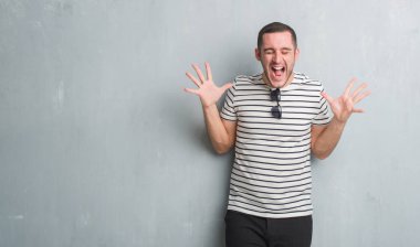 Gri grunge duvar kutluyor üzerinde beyaz delikanlı deli ve silah ile başarı için deli kaldırdı ve heyecanlı çığlık gözler kapalı. Kazanan kavramı