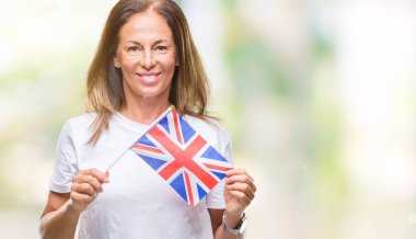 Amerika Birleşik Devletleri bayrağı ayakta ve diş gösterilen kendine güvenen bir gülümsemeyle gülümseyerek mutlu bir yüz ile izole arka plan üzerinde tutan orta yaş İspanyol kadın