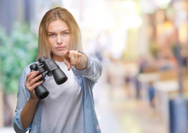 Genç kafkas kadın holding dürbün kamera ve size parmak ile işaret izole arka plan üzerinde el işareti, pozitif ve kendinden emin bir jest ön