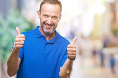 Orta yaş ağarmış komuta sizde izole arka plan başarı işareti el ile pozitif jest yapıyor üzerinde başparmak gülümseyen ve mutlu. Neşeli bir ifadeyle, kazanan jest kameraya bakıyor.
