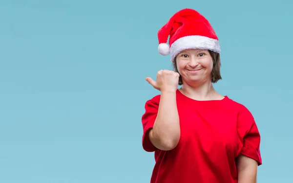 有唐氏综合症的年轻成年妇女戴着圣诞帽在孤独的背景微笑着快乐的脸看着 指向侧面与拇指向上 — 图库照片