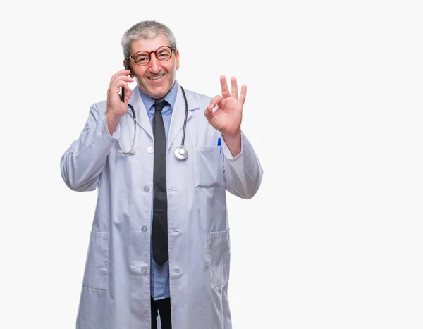 英俊的高级医生男子谈论 Smarpthone 在孤立的背景做 符号与手指 优秀的符号 — 图库照片