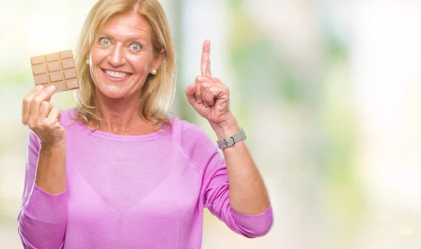 Blonde Frau Mittleren Alters Isst Schokoriegel Über Isoliertem Hintergrund Überrascht — Stockfoto