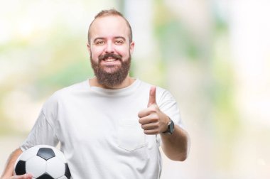 Futbol futbol topu tutan genç beyaz hipster adam arka plan mutlu ok işareti, başparmak ile parmak, mükemmel işareti yapıyor kocaman bir gülümseme ile izole