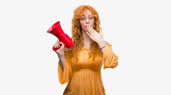 Молодая Рыжая Женщина Держащая Мегафон Прикрывает Рот Рукой Потрясенной Стыдом — стоковое фото