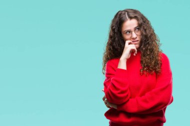 Stresli ve gergin elle çivi ısırma ağzına bakarak izole arka plan üzerinde gözlük ve kış kazak giyen güzel esmer kıvırcık saçlı Genç kız. Anksiyete sorunu.