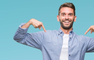 Yüzünde gülümseme ile kendinden emin görünüyorsun, kendini gururlu ve mutlu parmakları ile işaret izole arka plan üzerinde beyaz t-shirt giyen genç yakışıklı adam.