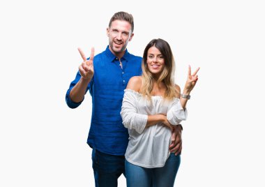 Mutlu yüz zafer işareti yaparken kameraya göz kırpıyor ile gülümseyen izole arka plan üzerinde aşık genç bir çift. İki numaralı.