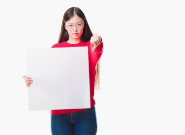 Genç Çinli kadın yüzünden kızgın yüzü ile boş başlık, başparmak aşağı ile eksi işareti gösteren sevmemek, ret kavramı holding arka plan izole