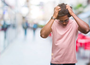 Çünkü çaresiz ve stresli baş ağrısı acı izole arka plan üzerinde güneş gözlüğü takıyor Afro Amerikalı adam ağrı ve migren. Ellerini kafasına.