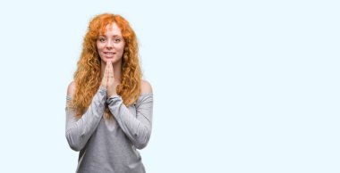 El ele tutusun AF emin gülümseyen için soran ile dua genç Kızıl saçlı kadın.