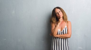 Gri grunge duvar ciddi bir yüz düşünme hakkında soru, çok karışık bir fikir üzerinde duran orta yaş İspanyol kadın