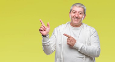 Üst düzey yakışıklı gülümseyen ve iki elleri ve parmakları ile tarafına işaret kamera bakarak izole arka plan üzerinde spor giyim eşyası.