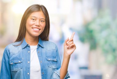 Kameraya bakarak yan el ve parmak ile işaret eden Genç Asyalı kadın yüzünde kocaman bir gülümseme ile izole arka plan üzerinde.