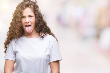 Güzel esmer kıvırcık saçlı Genç kız dilini izole arka plan üzerinde rahat t-shirt giyen out komik ifade ile mutlu. Duygu kavramı.