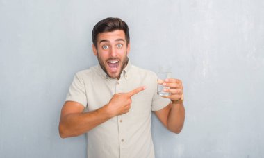 El ve parmak ile işaret çok mutlu su içme gri grunge duvarın üzerinden yakışıklı genç