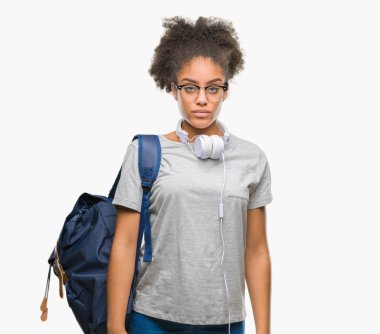 Yüzünde ciddi bir ifade ile izole arka plan üzerinde kulaklık ve sırt çantası giyen genç afro Amerikan öğrenci kadın. Basit ve doğal kameraya bakıyor.