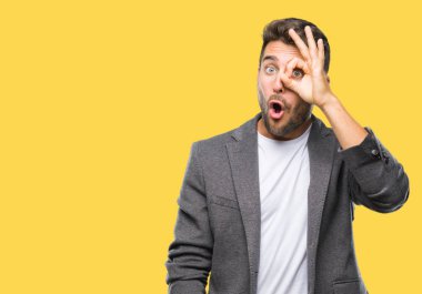 Genç yakışıklı iş adamı ok jest yapıyor izole arka plan üzerinde sürpriz yüz, göz parmaklarının arasından seyir ile şok. İmansız ifade.