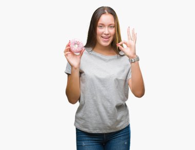 Parmak, mükemmel sembolü ile ok işareti yapıyor izole arka plan üzerinde tatlı çörek yiyen genç kafkas kadın