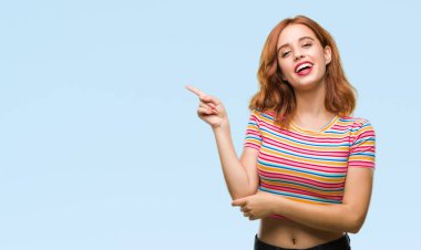 Kameraya bakarak yan el ve parmak ile işaret izole arka yüzünde kocaman bir gülümseme ile genç güzel kadın.