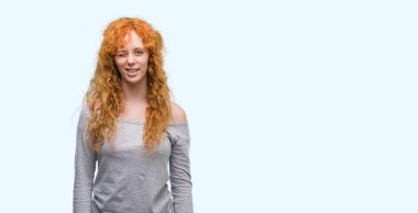 Genç Kızıl saçlı kadın seksi bir ifadeyle, neşeli ve mutlu yüzünü kameraya bakarak göz kırpıyor.