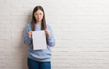 Kendinden emin bir ifade ile boş kağıt ciddi düşünme acımak yüz tutan tuğla duvarın üzerinden Genç Çinli kadın