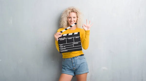 Jovem Mulher Loira Sobre Grunge Parede Cinza Segurando Painel Calçado — Fotografia de Stock