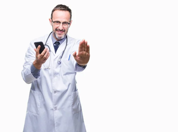 中年老年医生短信使用智能手机在孤立的背景下 张开手做停止标志 认真和自信的表达 防御姿态 — 图库照片