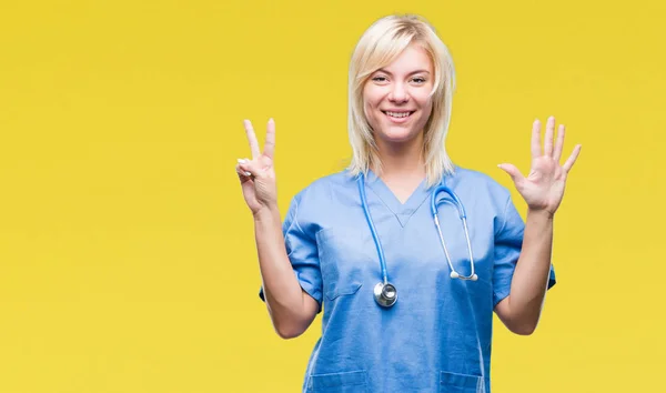 Young beautiful blonde doctor woman wearing medical uniform over isolated background showing and pointing up with fingers number seven while smiling confident and happy.