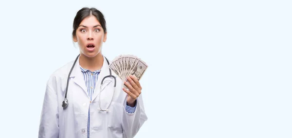 Joven Doctora Hispana Sosteniendo Dólares Asustada Shock Con Una Cara — Foto de Stock