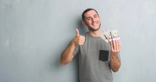 Young Caucasian Man Grey Grunge Wall Holding Bunch Money Happy — Stock Photo, Image