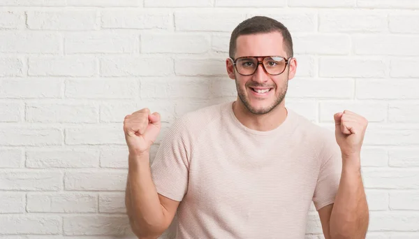 Jovem Caucasiano Sobre Parede Tijolo Branco Usando Óculos Gritando Orgulhoso — Fotografia de Stock