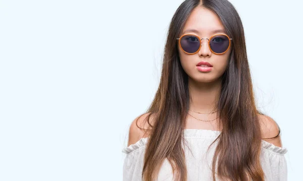 Junge Asiatin Mit Sonnenbrille Über Isoliertem Hintergrund Mit Ernstem Gesichtsausdruck — Stockfoto