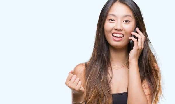 Молодая Азиатка Говорящая Телефону Изолированном Фоне Гордо Крича Празднуя Победу — стоковое фото