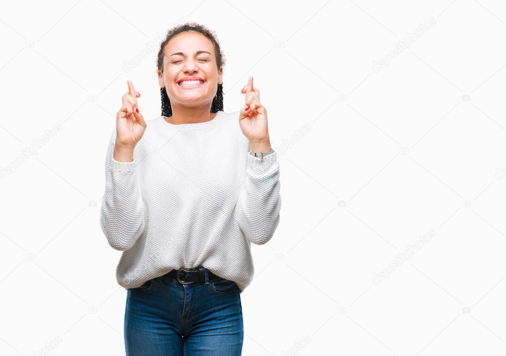 Young braided hair african american girl wearing winter sweater over isolated background smiling crossing fingers with hope and eyes closed. Luck and superstitious concept.