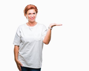 Atrractive üst düzey beyaz Kızıl saçlı kadın neşeli sunulması ve kameraya bakarak avucunun ile işaret gülümseyen izole arka plan.