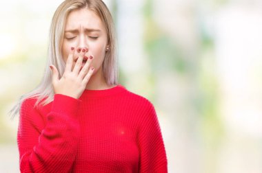 İzole arka plan üzerinde esneme sıkılmış kış kazak giyen genç sarışın kadın kapsayan ağız el ile yorgun. Restless ve uyku hali.