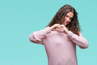 Güzel esmer kıvırcık saçlı Genç kız kalp simgesi ve elleriyle şekil gösterilen aşık gülümseyen izole arka plan üzerinde pembe kış kazak giyiyor. Romantik kavramı.