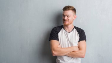 Gri grunge duvar görünümlü yan ve dik dik bakma uzağa düşünce gülümseyen genç Kızıl saçlı adam.